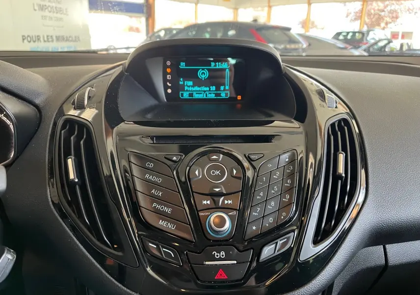 Tableau de bord noir de Ford B-MAX 2015 avec console centrale brillante et écran radio affichant la station FM.