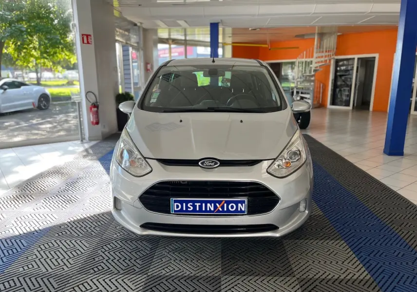 Vue avant d'une Ford B-MAX gris clair 2015 dans un showroom avec une plaque Distinxion visible.
