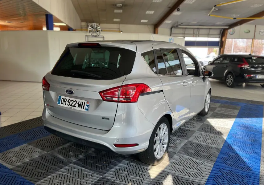 Vue 3/4 arrière droite d'une Ford B-MAX gris clair 2015 en intérieur avec vitres teintées et jantes alliage.