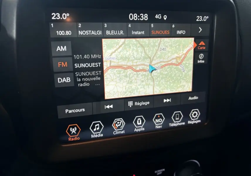 Écran tactile central affichant la navigation et la radio dans l'habitacle d'une Jeep Renegade bleu 2021.