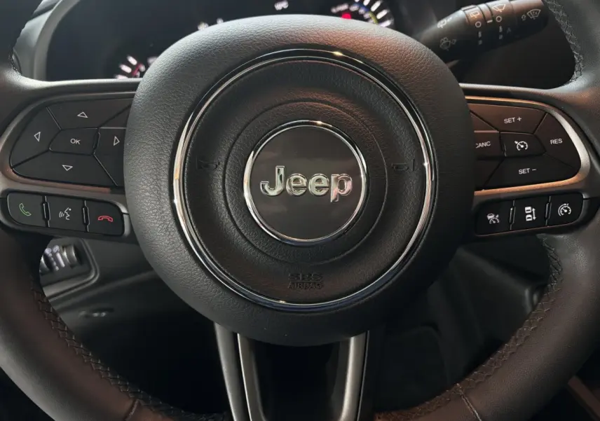 Gros plan sur le volant cuir multifonction Jeep du Renegade hybride rechargeable, avec commandes intégrées et airbag central.