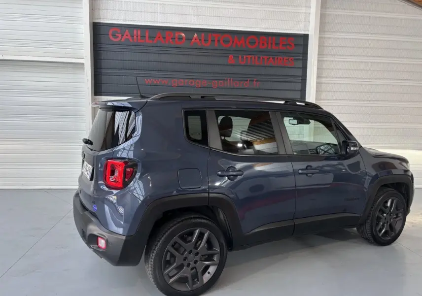 Jeep Renegade bleu en vue 3/4 arrière côté gauche, avec toit noir et jantes foncées dans un garage.