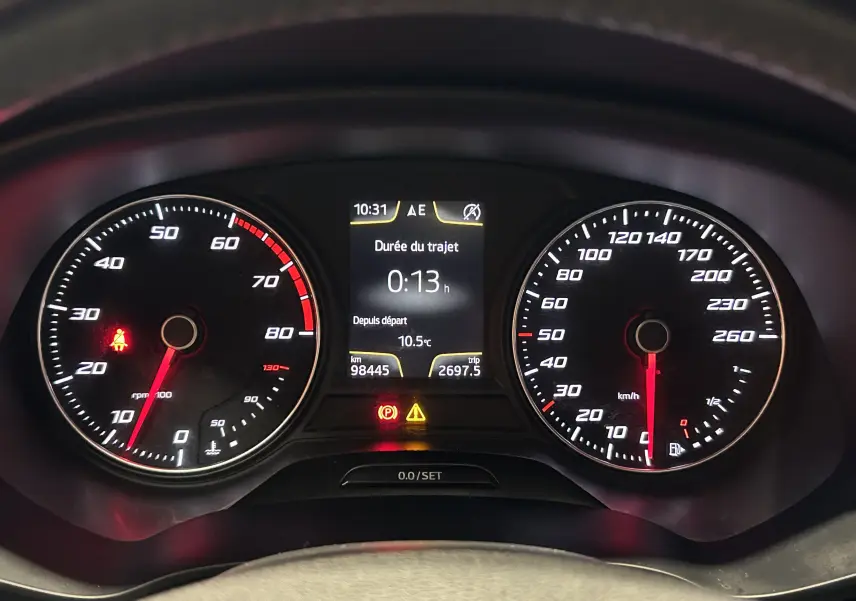 Tableau de bord du SEAT Leon 2014 noir, vue frontale des compteurs avec affichage digital central et voyants allumés.