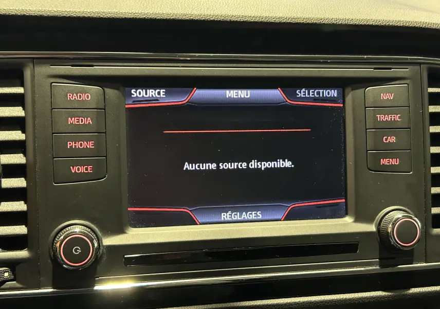 Écran central du système multimédia du SEAT Leon 2014 avec menu en français et boutons de commande rétroéclairés rouges.