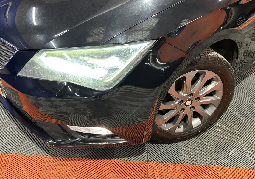 Gros plan sur l'avant droit noir d'une SEAT LEON 2014, mettant en valeur le phare et la jante alliage.