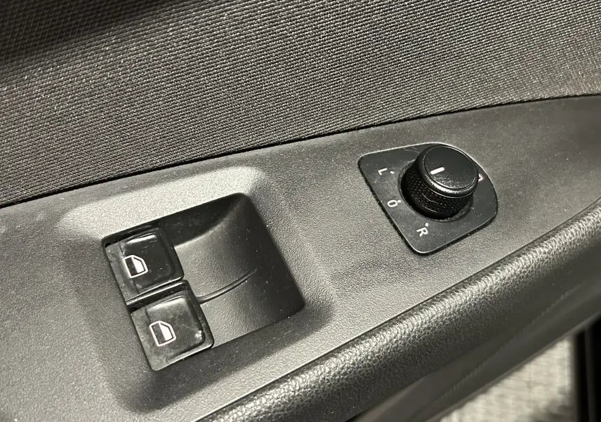 Gros plan sur les commandes de réglage des rétroviseurs et des vitres électriques côté conducteur d’une SEAT LEON noire.