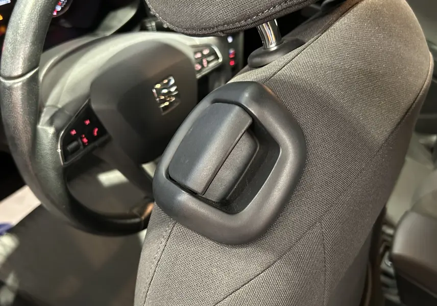 Gros plan sur l'appui-tête tissu noir du siège avant droit d'une SEAT LEON 2014, volant et tableau de bord en arrière-plan.