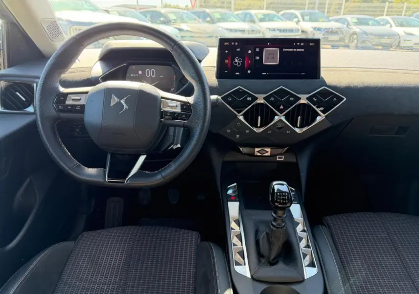 Vue intérieure avant du DS3 2024 gris, mettant en valeur le volant compact et la boîte manuelle au design moderne.