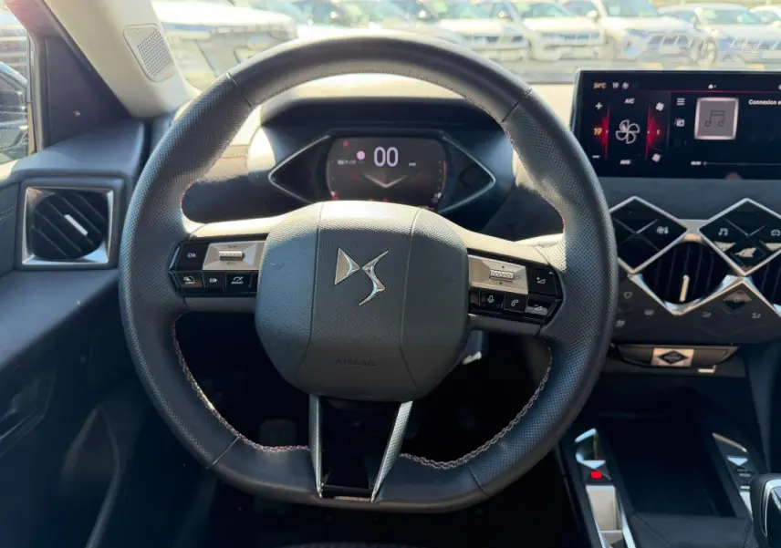Vue intérieure centrée sur le volant du DS3 2024 gris, avec tableau de bord numérique et commandes intégrées au volant.