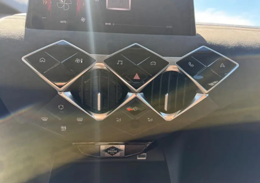 Vue rapprochée de la console centrale du DS3 2024 gris, avec commandes tactiles en losange et aérateurs ronds.