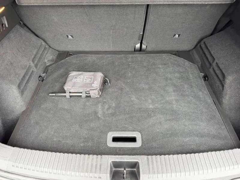 Coffre ouvert vu de dessus d’un Renault Austral 2025, tapis gris avec kit de sécurité posé à gauche.