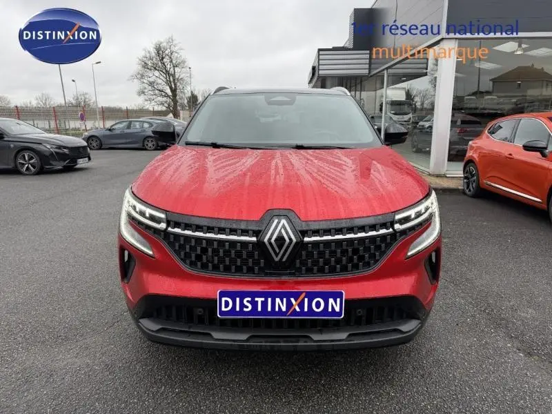 Vue frontale d'un Renault Austral 2025 rouge flamme avec calandre noire à motif damier et logo Renault central.
