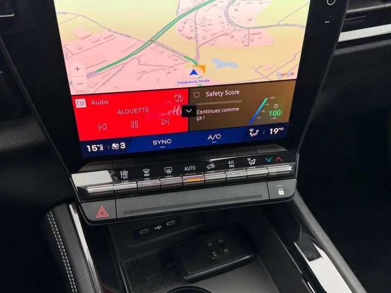 Gros plan sur l’écran tactile central et la console de la Renault Austral rouge, affichant la navigation et les commandes climatisation.