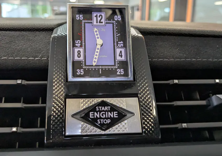 Gros plan sur l'horloge analogique et le bouton start/stop du tableau de bord du DS7 gris laqué, version Pallas 2025.