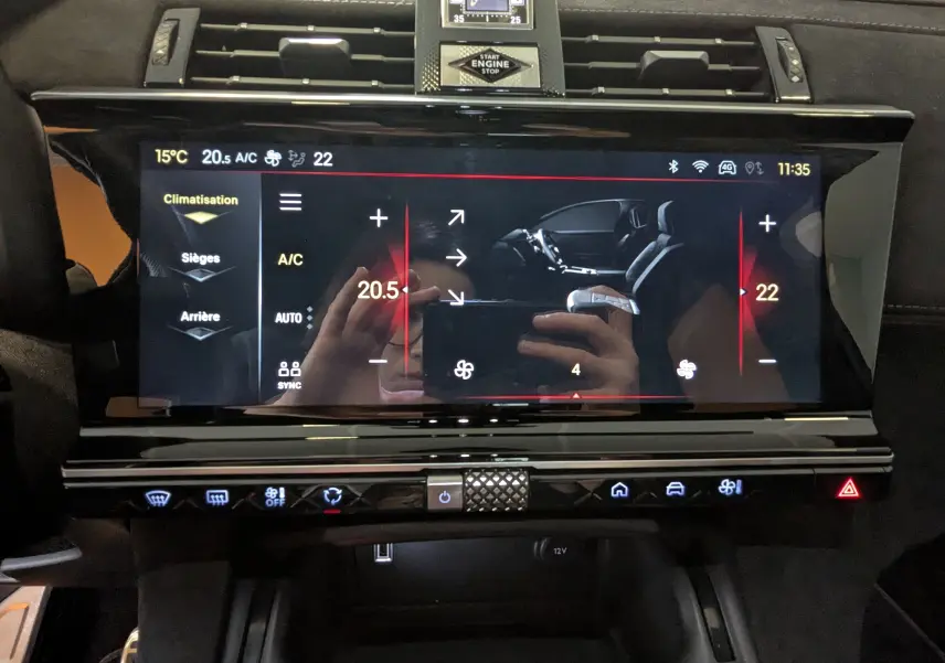 Écran tactile central de la DS7 gris laque, affichant la climatisation avec commandes digitales et horloge analogique au-dessus.