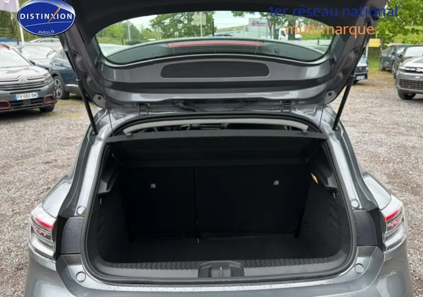 Vue arrière ouverte sur le coffre spacieux d'une Renault Clio V gris schiste, avec feux arrière LED visibles.