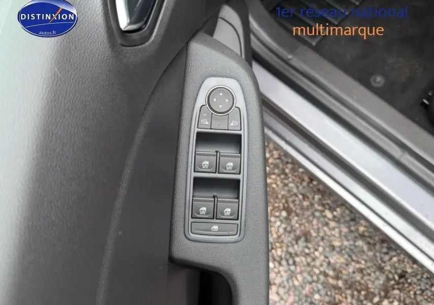 Vue rapprochée des commandes des vitres électriques sur la porte côté gauche d'une Renault Clio V gris schiste.