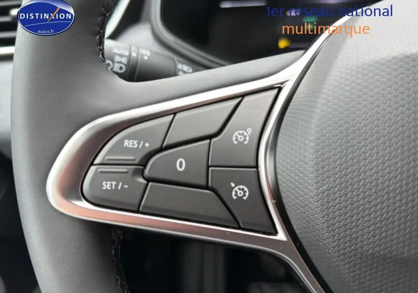 Gros plan sur les commandes de régulateur de vitesse au volant d'une Renault Clio V gris schiste, intérieur moderne.