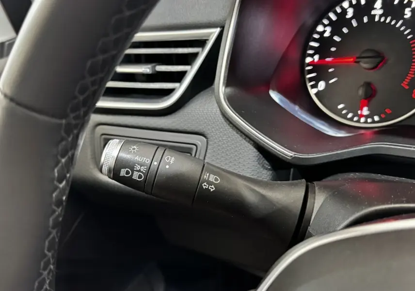 Gros plan sur la manette de commandes des phares et clignotants dans l’habitacle gris foncé de la Renault Clio Business TCe 90.