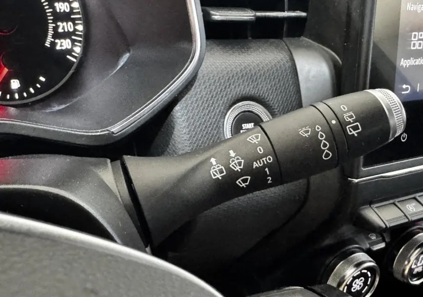 Gros plan sur la commande d’essuie-glace à gauche du volant dans l’habitacle noir de la Renault Clio Business TCe 90 gris clair.