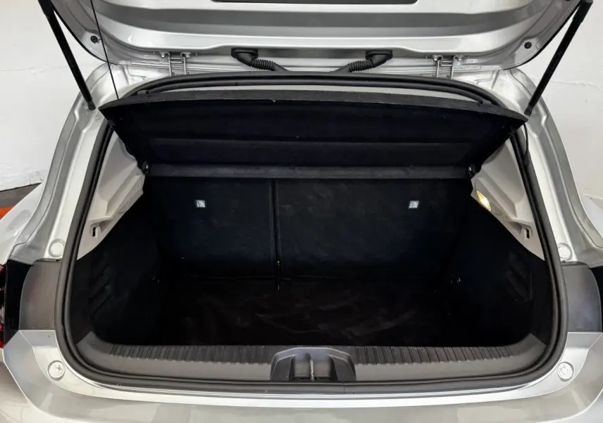Coffre ouvert vu de l'arrière d'une Renault Clio Business TCe 90 gris clair, montrant l'espace de chargement vide et la tablette arrière relevée.