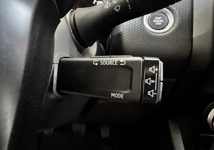 Gros plan sur la commande multifonction noire côté gauche du volant d’une Renault Clio gris clair 2020 avec bouton Start Engine Stop visible.