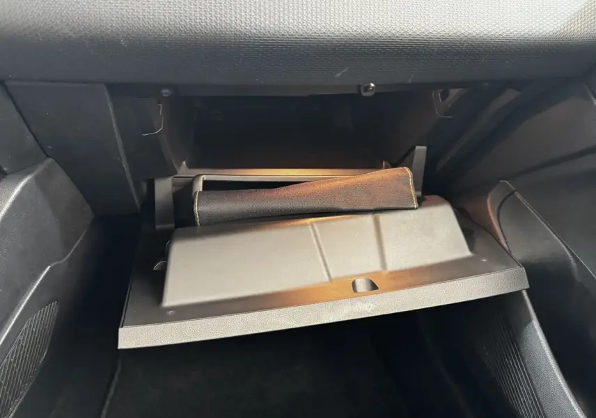 Gant de boîte à gants ouvert dans l'habitacle noir d'une Renault Clio Business TCe 90 gris clair, vue côté passager.