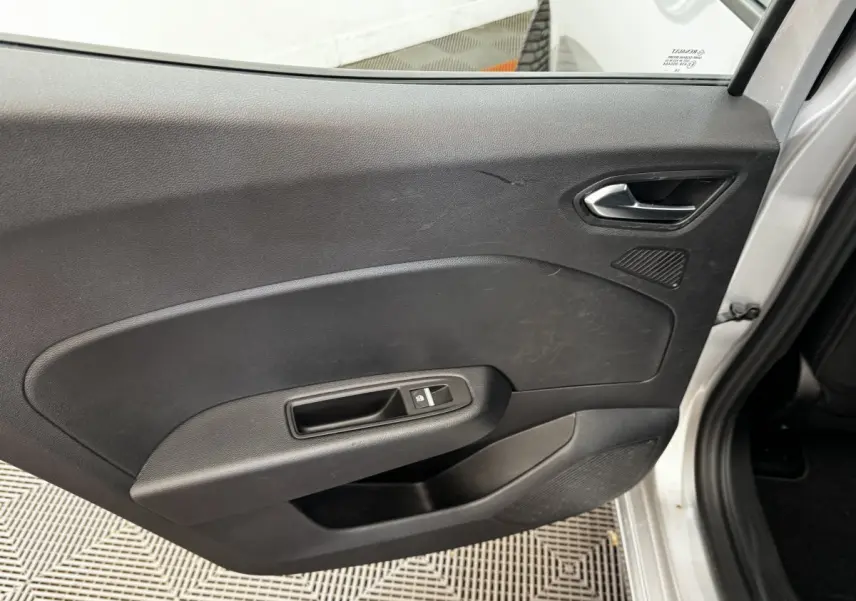 Vue intérieure côté droit de la porte arrière grise claire de la Renault Clio Business TCe 90 avec poignée et commande de vitre électrique.