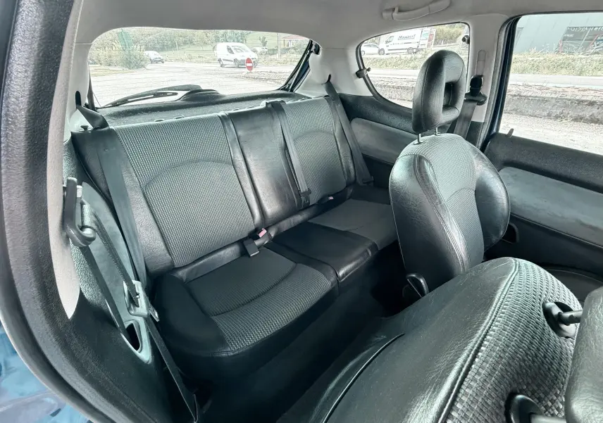 Intérieur arrière de la Peugeot 206 bleu, vue côté droit montrant les sièges en cuir et tissu noir.