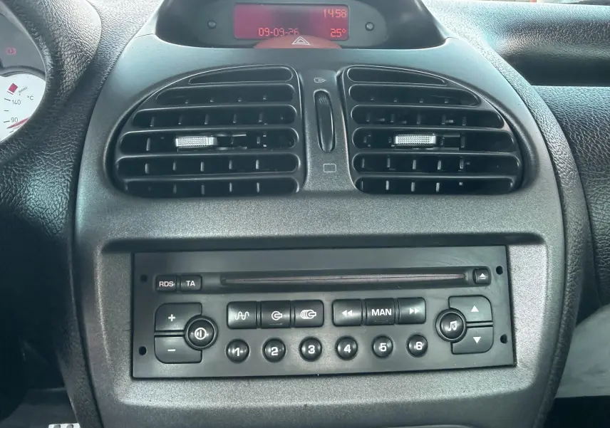 Vue rapprochée du tableau de bord noir de la Peugeot 206 bleu, montrant la radio et les aérateurs centraux.