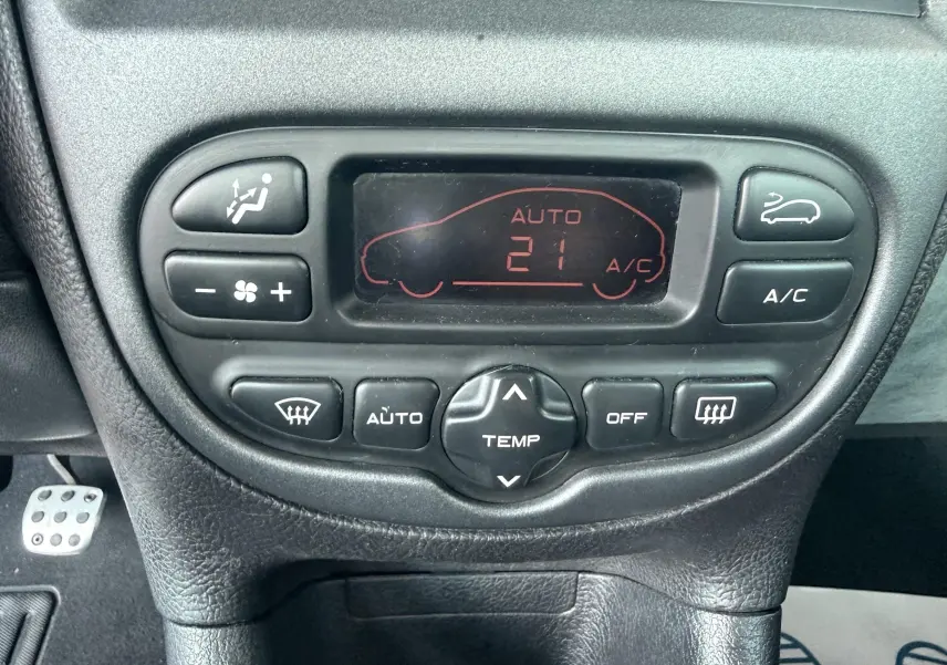 Vue rapprochée de la console de climatisation automatique avec écran digital et boutons noirs dans une Peugeot 206.