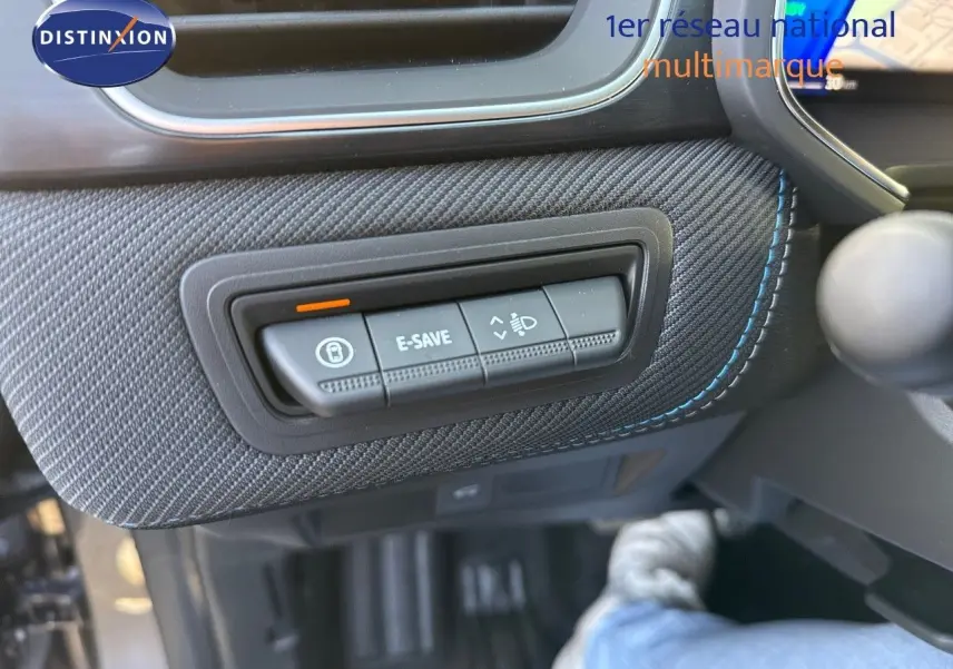 Gros plan sur les commandes E-SAVE et réglage des phares dans l’habitacle gris cassiopée métal du Renault Symbioz 2024.
