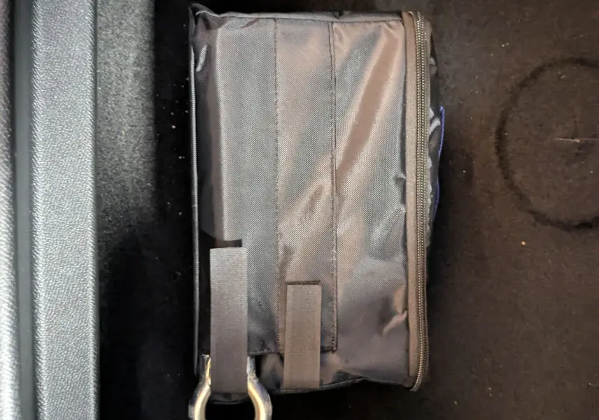 Gros plan sur un sac noir avec anneau métallique posé sur le tapis noir intérieur d’un Peugeot 3008 hybride.