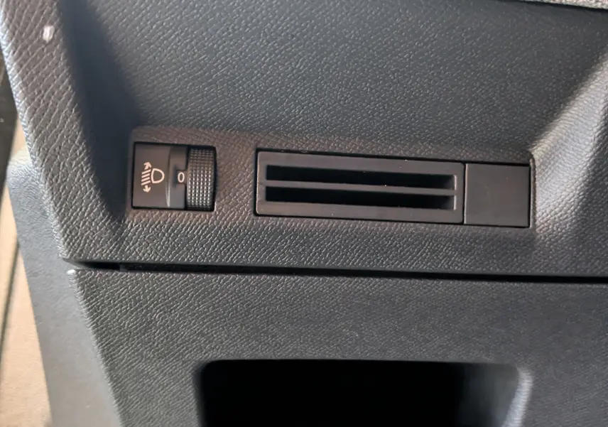 Détail du tableau de bord noir du Peugeot 3008 Hybrid 145, avec réglage de hauteur des phares et prise d'air.