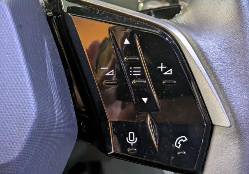 Gros plan sur les commandes noires du volant cuir côté gauche du Peugeot 3008 Hybrid 145 Allure 2025.