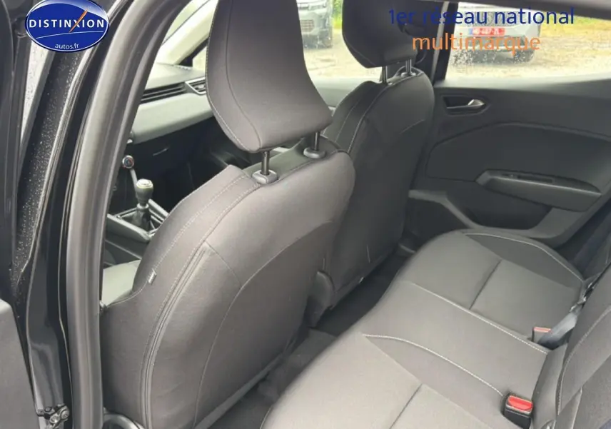 Vue intérieure côté droit arrière de la Renault Clio V noire, montrant les sièges et la boîte manuelle à l'avant.