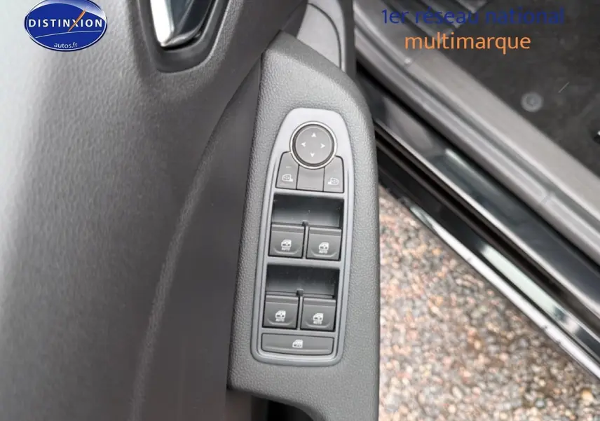 Gros plan sur les commandes des vitres électriques côté conducteur d'une Renault Clio V noire, avec porte ouverte.