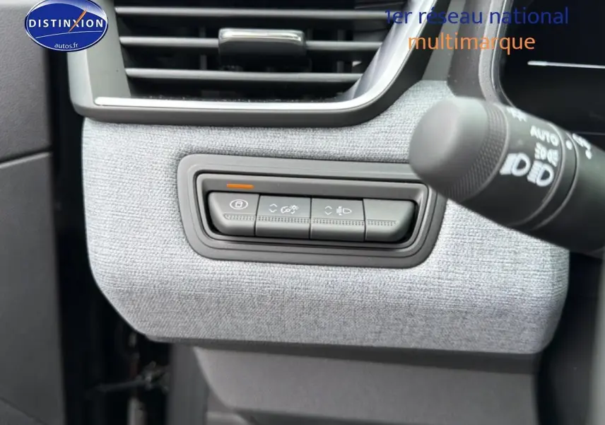 Détail des commandes d'éclairage et verrouillage sur tableau de bord gris clair d'une Renault Clio V noire.