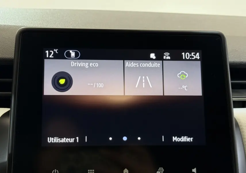 Écran tactile central de la Renault Clio blanc 2023 affichant les aides à la conduite et la température extérieure.