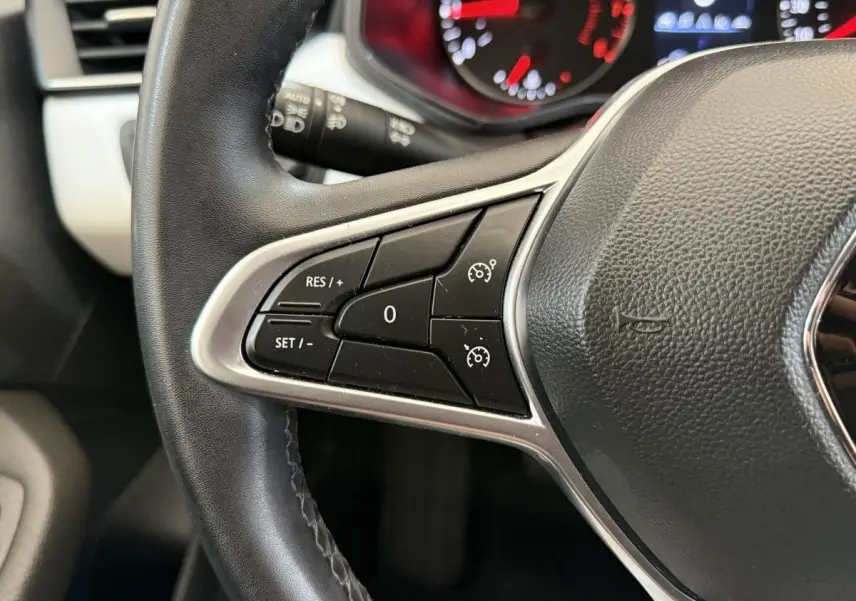 Gros plan sur le volant cuir synthétique de la Renault Clio 2023 avec commandes de régulateur de vitesse visibles.