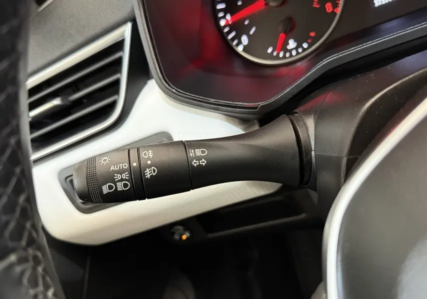 Gros plan sur la commande des feux et clignotants à gauche du volant dans une Renault Clio blanche 2023.