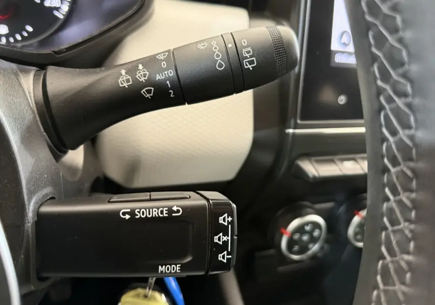 Gros plan sur les commandes des essuie-glaces et multimédia à gauche du volant d’une Renault Clio blanche 2023.