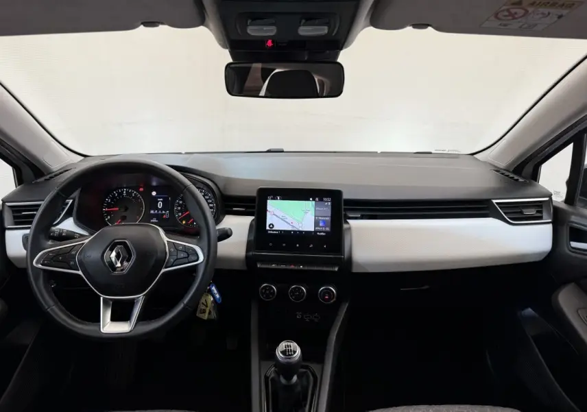 Vue frontale de l’habitacle de la Renault Clio blanche 2023, avec tableau de bord moderne et écran tactile central.