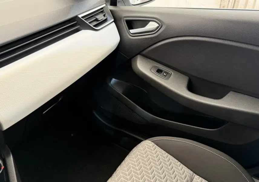 Intérieur côté passager de la Renault Clio blanc, montrant la porte noire et la partie basse du tableau de bord blanc.