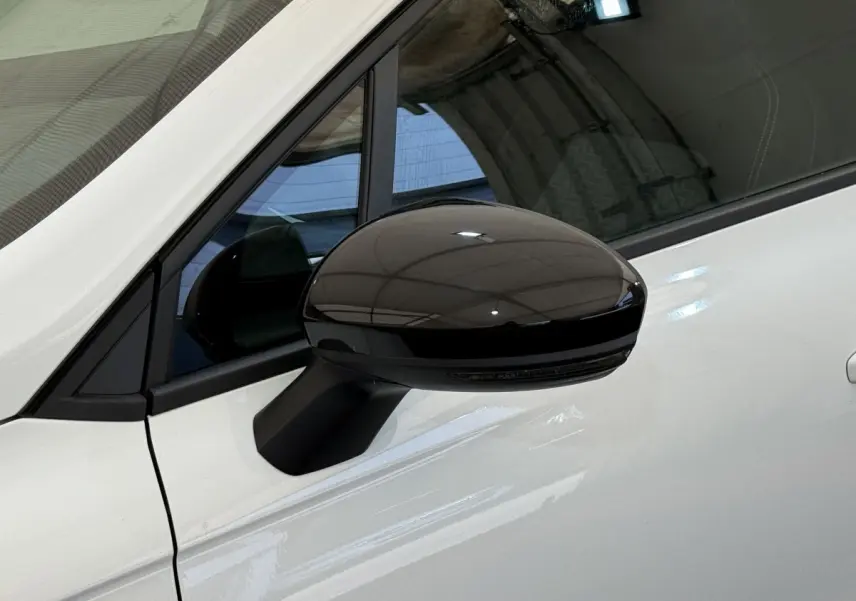 Rétroviseur noir côté gauche sur porte blanche d'une Renault Clio Evolution TCe 100 GPL 2023 vue de profil rapprochée.