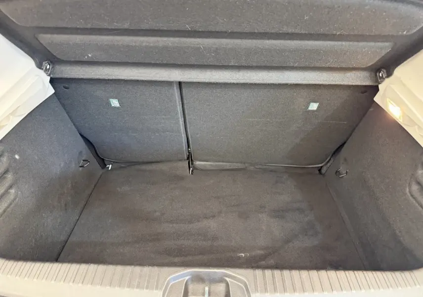 Vue intérieure du coffre ouvert d'une Renault Clio blanche 2023, montrant un espace de rangement propre et tapissé en tissu noir.