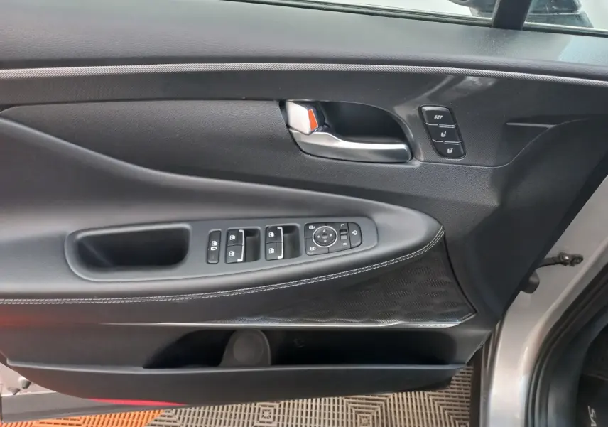 Vue intérieure côté conducteur de la porte gris clair du Hyundai Santa Fe 2022 avec commandes électriques et poignée métal.