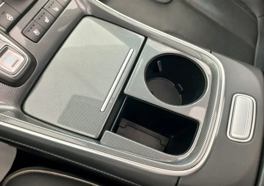 Gros plan sur la console centrale grise à effet carbone du Hyundai Santa Fe 2022, avec porte-gobelets et commandes.