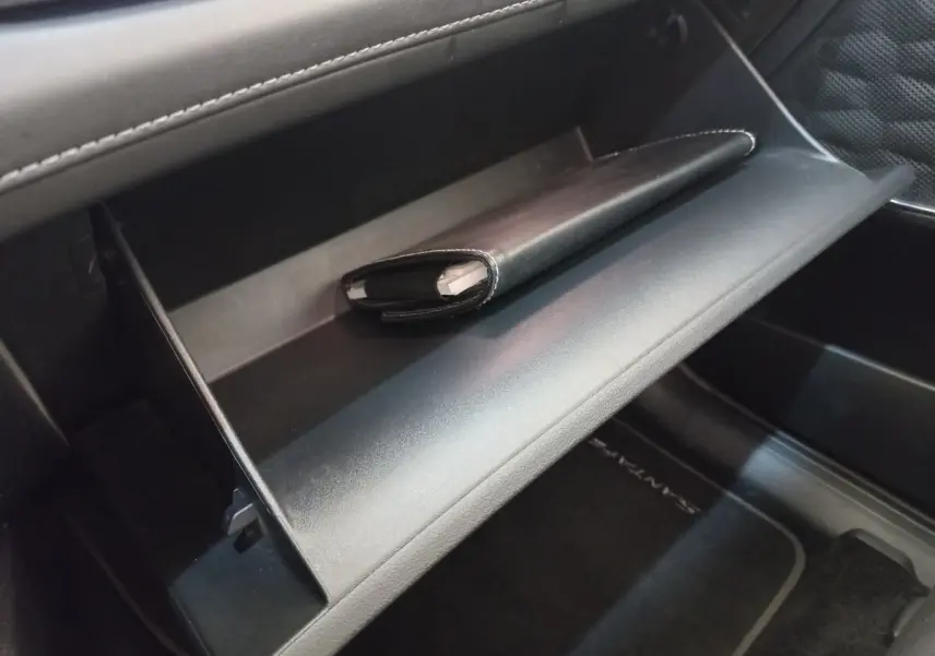 Vue intérieure du coffre à gants ouvert du Hyundai Santa Fe 2022 avec un étui noir posé à l'intérieur.