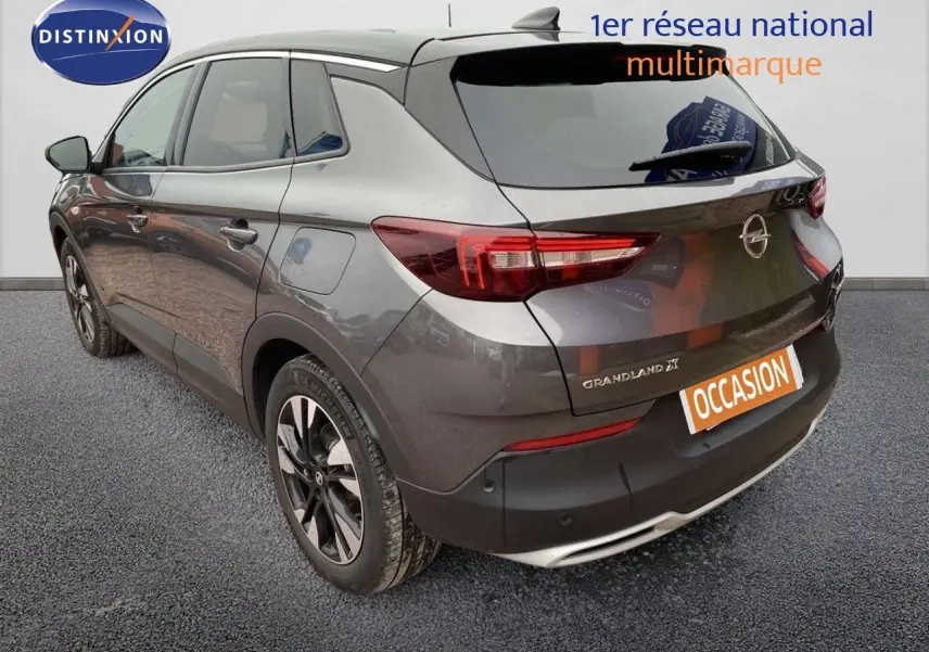 Vue 3/4 arrière droite d'un Opel Grandland X gris Moai Metal avec feux LED et jantes bicolores.